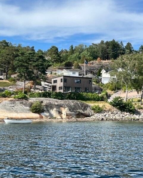 Denna moderna tappning på den klassiska fjällstugan beställdes av kund som ett fritidsboenden på en av Sveriges populära skidorter.
Huset är utvändigt klätt med svart panel och invändigt med en mörkbrun murrig panel. Den höga fönsterbeklädda gaveln vetter ut mot skidbacken och ger en vacker vidsträckt utsikt över landskapet från både allrummet och från loftets balkong. Den centrerade kaminen förstärker rummets höjd när det leder ögat upp.