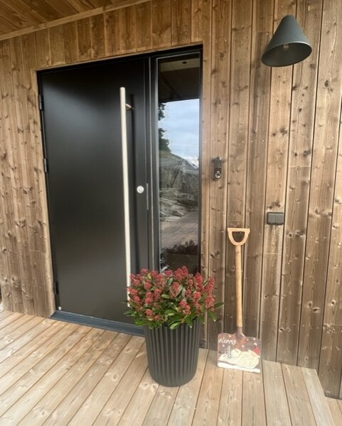 Denna moderna tappning på den klassiska fjällstugan beställdes av kund som ett fritidsboenden på en av Sveriges populära skidorter.
Huset är utvändigt klätt med svart panel och invändigt med en mörkbrun murrig panel. Den höga fönsterbeklädda gaveln vetter ut mot skidbacken och ger en vacker vidsträckt utsikt över landskapet från både allrummet och från loftets balkong. Den centrerade kaminen förstärker rummets höjd när det leder ögat upp.